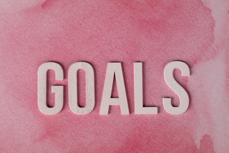 Motivational word 'GOALS' on a pink watercolor background for inspiration about native gardening goals.